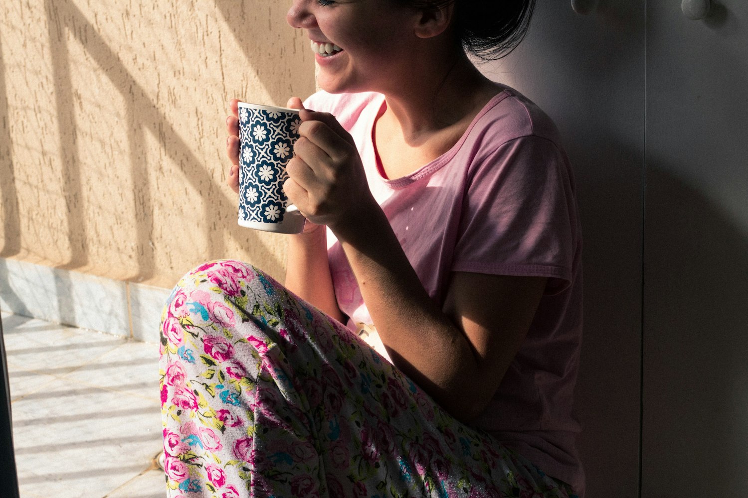 A mom in soft pink resting with a warm mug in a quiet moment of calm