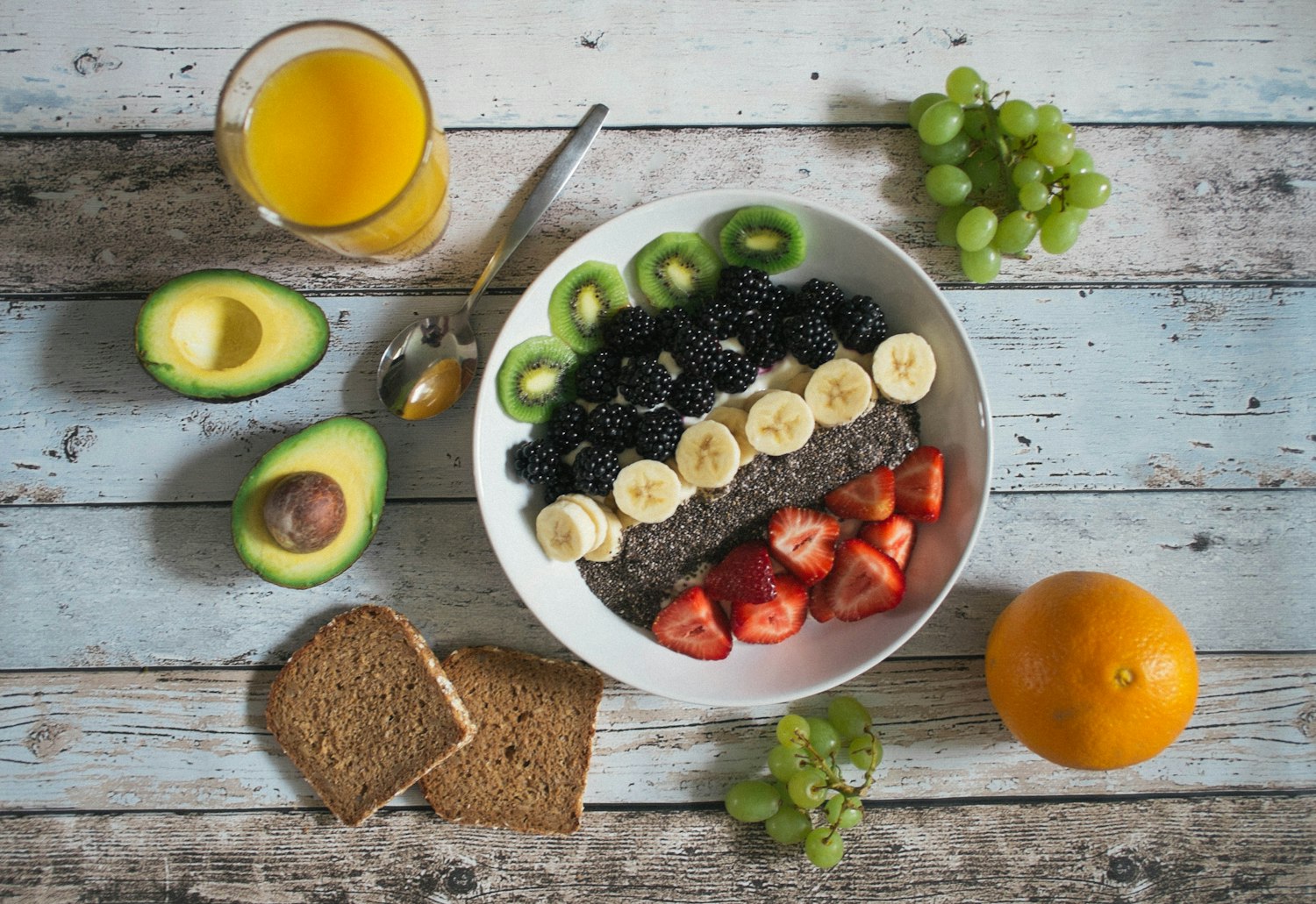 A colourful, wholesome breakfast bowl with fruit, avocado and juice