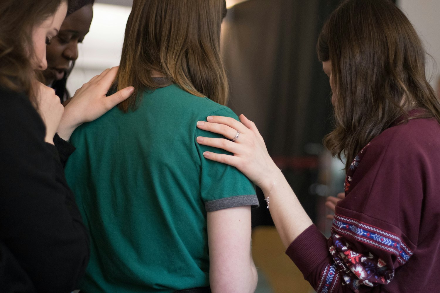 Hands resting gently on a woman's shoulders in a circle of support